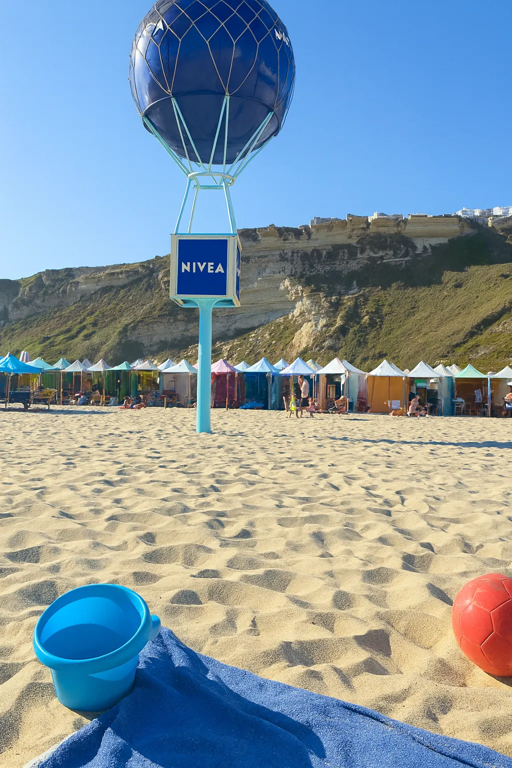 Structure NIVEA sur la plage de Nazaré devant les tentes colorées